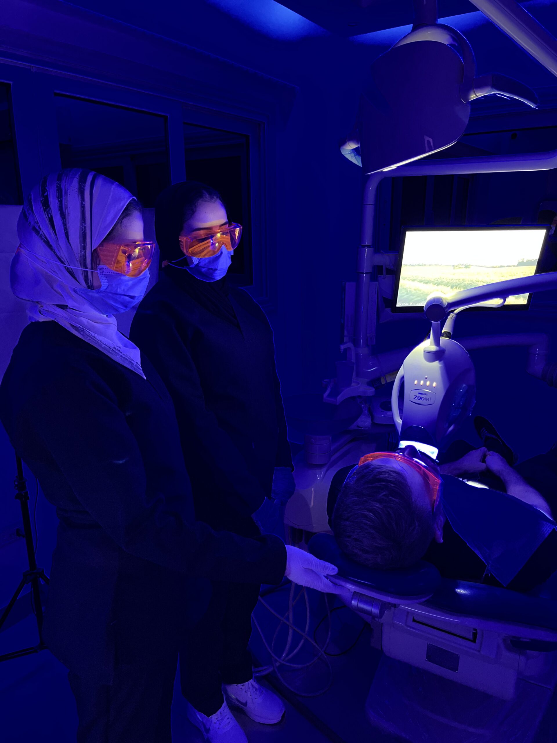 2 Dental assistants standing beside a patient doing zoom teeth whitening in a dental clinic in cairo